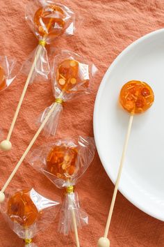 candy lollipops are sitting on a white plate next to some orange candies