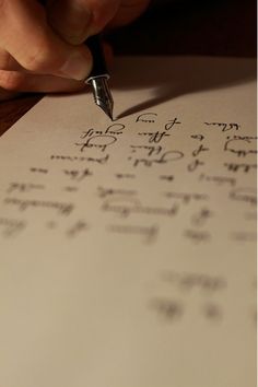 a person writing on a piece of paper with a fountain pen in their left hand