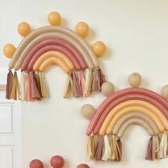 two balloons are hanging on the wall with a rainbow and tassels attached to it