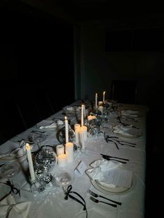 a long table is set with candles and place settings for an elegant dinner or party