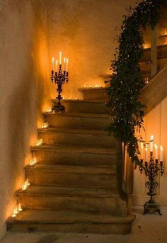 black and white photograph of stairs with lit candles on each handrail in an old house