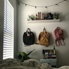 three purses are hanging on the wall above a bed