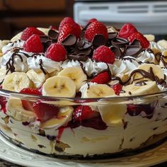 a cake with bananas, strawberries and chocolate on top is sitting on a plate