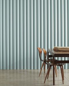 three chairs and a table in front of a wall with vertical slats on it