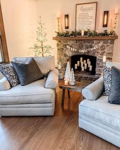 a living room with two couches and a christmas tree in front of the fireplace