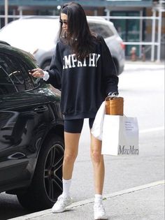 a woman walking down the street while looking at her cell phone