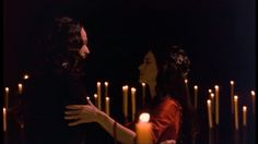 two people standing next to each other in front of candles