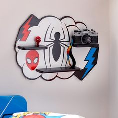 there is a camera on the shelf in front of this wall clock that has a spiderman design