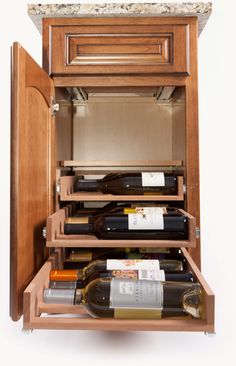 a wooden cabinet with two wine glasses and bottles in it on top of a white wall