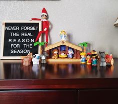 an elf is sitting on top of a shelf next to a christmas nativity scene