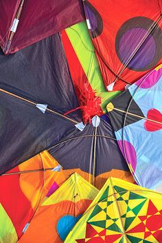 many colorful kites are laying on the ground together, some with holes in them