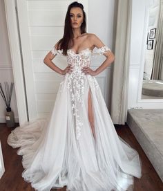 a woman in a white wedding dress standing on a wooden floor with her hands on her hips