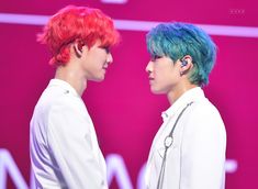 two young men with colorful hair standing next to each other on a pink stage backdrop