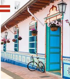 a bike parked in front of a building with blue shutters and flowers on the windows