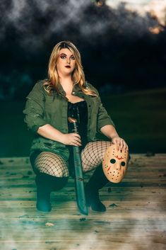 a woman sitting on a wooden floor holding a baseball bat and wearing fish net tights