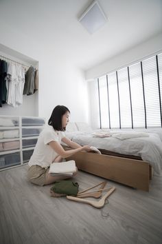 a woman sitting on the floor next to a bed