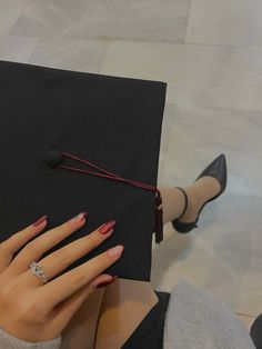 a woman's hand holding a black graduation cap with a diamond ring on it