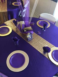 purple and gold table setting with plates, napkins and flowers on the centerpiece