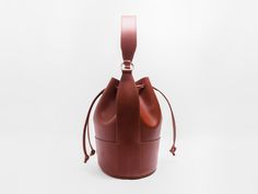 Our interpretation of a classic-- the bucket bag. Utilitarian, minimal, still sophisticated and beautiful. In our beloved Buttero leather from Italy. Balloon shaped body for rich, soft pleats when the drawstrings are pulled tight. Roomy interior to carry all your necessities.Featuring a handle along with a detachable shoulder strap, easily making this an everyday, carry-all bag. Gold finish brass hardware. Lined interior. Made with the finest, full grain Italian vegetable tanned leather. This le Cognac Bucket Bag For Office, Elegant Cognac Bucket Bag For Formal Occasions, Modern Cognac Bucket Bag With Removable Pouch, Modern Cognac Bucket Bag For Formal Occasions, Luxury Cognac Bucket Bag, Elegant Cognac Bucket Bag For Office, Formal Cognac Tote Bucket Bag, Timeless Travel Bucket Bag, Modern Cognac Bucket Bag