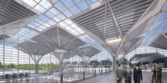 people are walking through an airport lobby with large windows on the ceiling and skylights above them