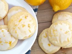 lemon cookies with icing on a plate next to two lemons and an orange