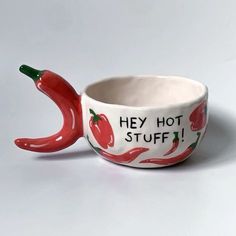 a ceramic bowl with red peppers painted on it and the words hey hot stuff in black lettering