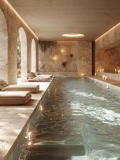 an indoor swimming pool with lounge chairs and candles in the water next to each other