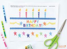 the birthday card is next to some scissors and tape on top of paper with candles