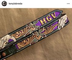 a purple and black belt with an eagle design on the bottom, and gold lettering that says hgtv