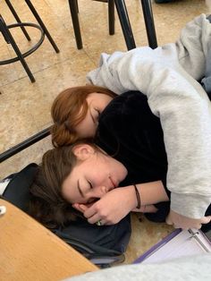 two people laying on the floor with their arms around each other and one person sleeping