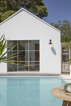 a house with a pool in front of it and a wooden table next to it