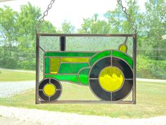 a stained glass window with a green tractor on it's side and trees in the background