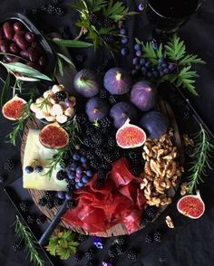 an assortment of fruits and cheeses on a platter with grapes, figs, walnuts