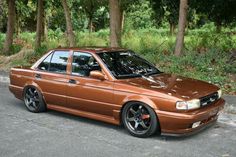 a brown car parked in front of some trees