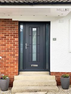 the front door of a house with two planters on it's side steps