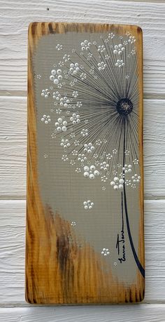 a dandelion painted on a wooden plaque with white paint sprinkles