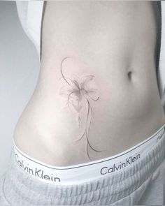 a woman's stomach with a flower tattoo on her lower back and the bottom part of her abdomen