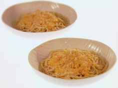 two bowls filled with noodles on top of a white tablecloth covered table next to each other