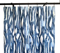 a blue and white curtain hanging from a metal rod with an abstract design on it