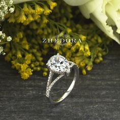 a diamond ring sitting on top of a table next to flowers