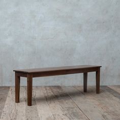 a wooden table sitting on top of a hard wood floor next to a white wall