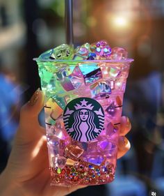 a hand holding a starbucks drink with lots of ice cubes in it's cup