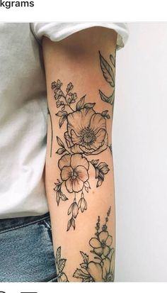 a woman's arm with flowers and leaves tattooed on the left side of her arm