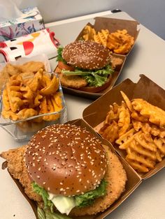 three trays filled with different types of burgers and french fries on a table