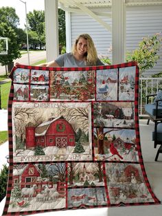 a woman standing in front of a red barn holding up a quilted christmas scene