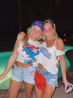 two women standing next to each other near a pool