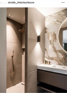 a bathroom with a sink, mirror and shower head mounted to the side of the wall