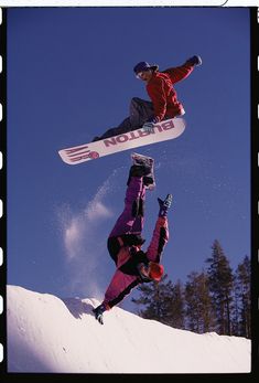 two snowboarders are doing tricks in the air