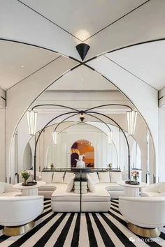 a living room filled with white furniture and black and white striped flooring on top of a hard wood floor