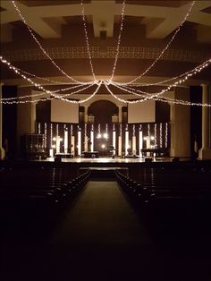 the inside of a church with rows of pews and lights strung from the ceiling